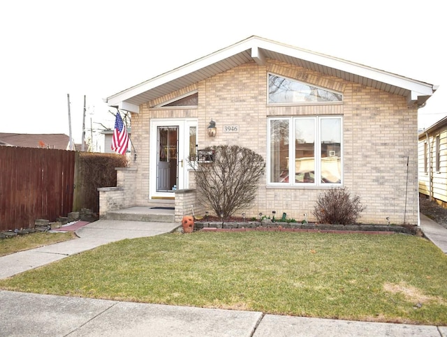 view of front of home featuring a front lawn, fence, and brick siding