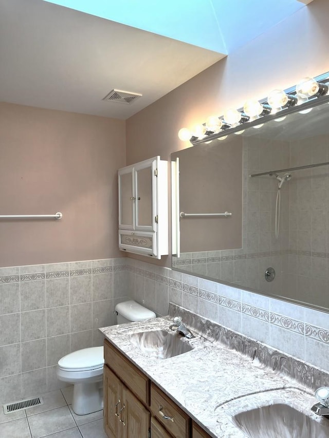 full bathroom with tile walls, visible vents, a sink, and tile patterned flooring