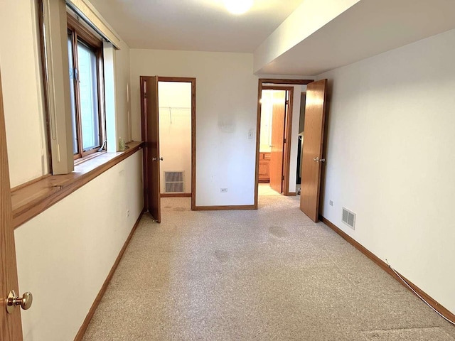 unfurnished bedroom with baseboards, light colored carpet, and visible vents
