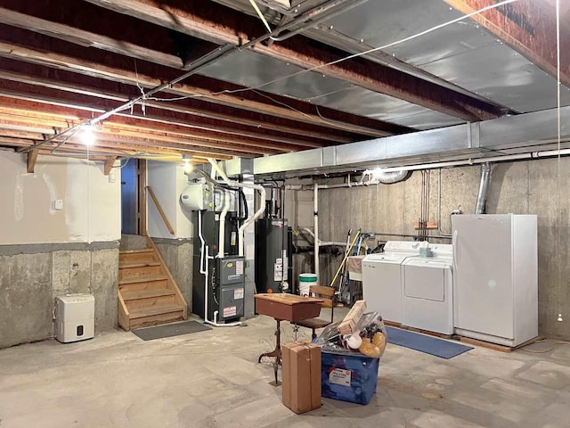 unfinished below grade area with gas water heater, stairway, heating unit, washer and clothes dryer, and freestanding refrigerator