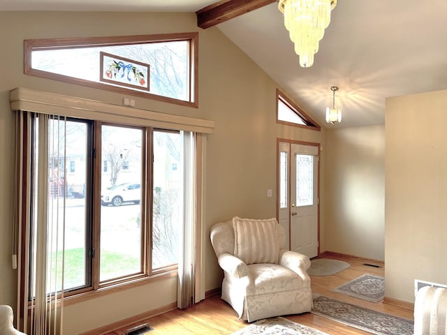 living area featuring light wood finished floors, baseboards, beamed ceiling, and a chandelier