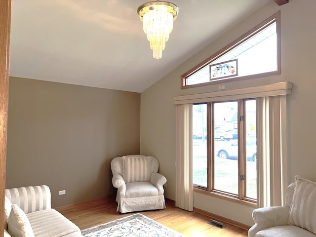 sitting room with baseboards, light wood-type flooring, an inviting chandelier, and vaulted ceiling