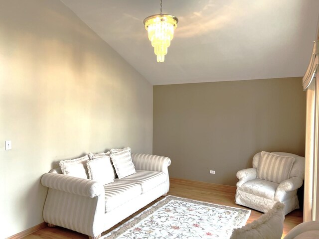 living room with vaulted ceiling, wood finished floors, and a chandelier
