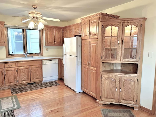 kitchen with light countertops, a sink, a ceiling fan, light wood finished floors, and white appliances