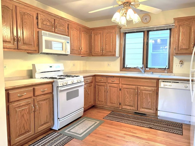 kitchen featuring light countertops, a sink, ceiling fan, and white appliances