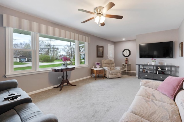 carpeted living room featuring a ceiling fan and baseboards