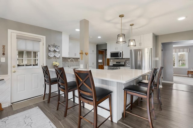 kitchen with a peninsula, white cabinets, appliances with stainless steel finishes, and light countertops