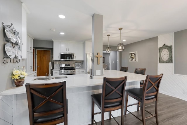 kitchen featuring a sink, a breakfast bar, a peninsula, light countertops, and appliances with stainless steel finishes