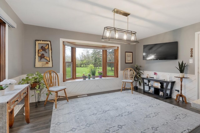 living area with dark wood-style flooring, visible vents, and a wainscoted wall