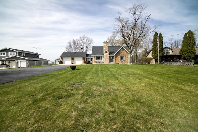 493 W Chebanse Ave, Chebanse, IL 60922 - view of front facade featuring a chimney, driveway, stone siding, an attached garage, and a front yard