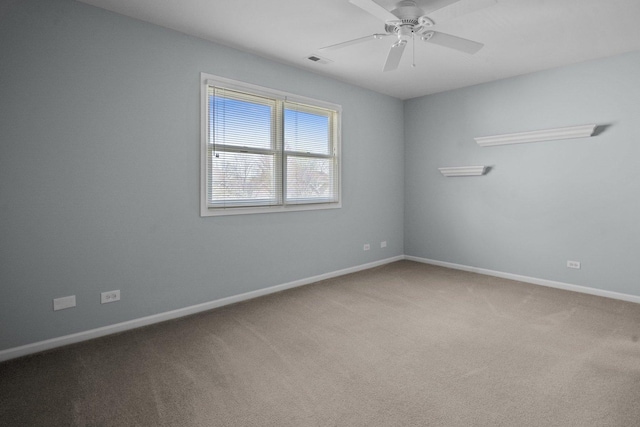 carpeted spare room featuring baseboards, visible vents, and ceiling fan