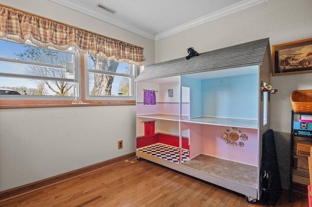 bedroom with crown molding, baseboards, wood finished floors, and visible vents