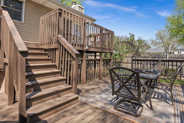 wooden terrace with stairs, fence, and outdoor dining space