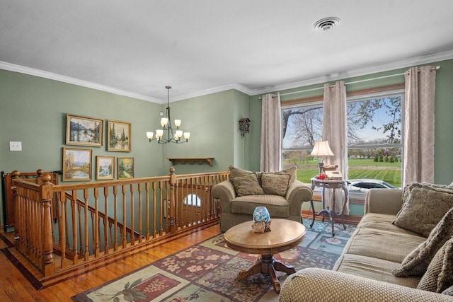 living room with crown molding, wood finished floors, a chandelier, and visible vents