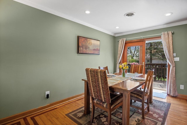 dining room with crown molding, baseboards, light wood-type flooring, and visible vents
