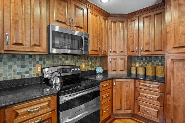 kitchen featuring dark stone countertops, appliances with stainless steel finishes, and brown cabinets