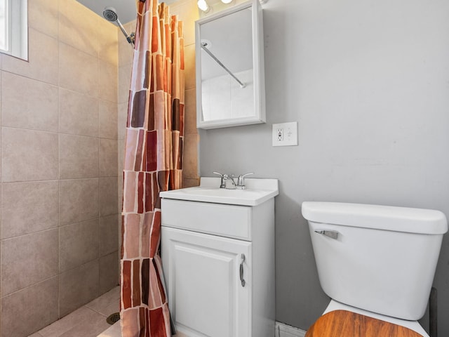 full bathroom with a tile shower, toilet, and vanity