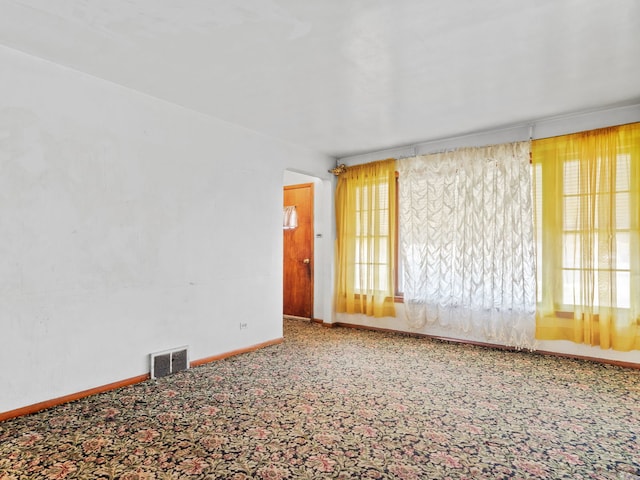 unfurnished room featuring baseboards, carpet, a healthy amount of sunlight, and visible vents