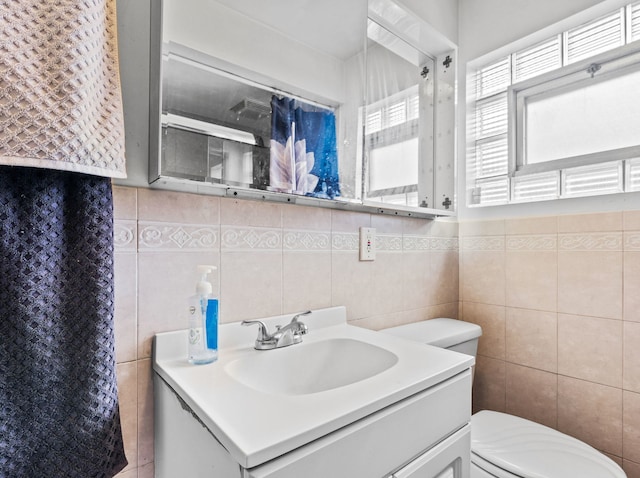 bathroom with tile walls, toilet, and vanity
