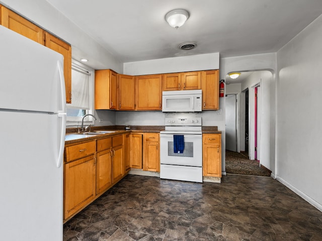 kitchen featuring visible vents, white appliances, dark countertops, a sink, and brown cabinetry