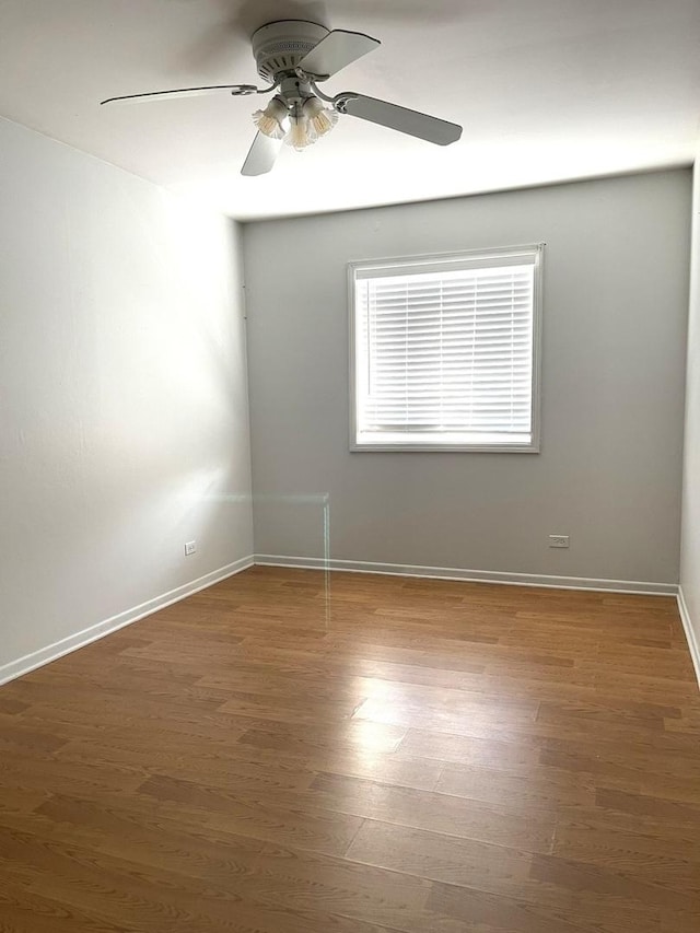 unfurnished room with baseboards, wood finished floors, and ceiling fan