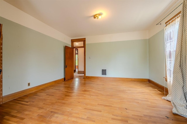empty room with baseboards, plenty of natural light, and light wood-type flooring