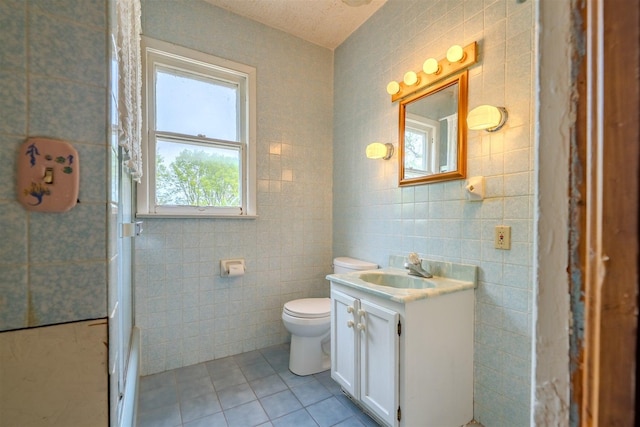 bathroom featuring vanity, tile walls, toilet, and tile patterned floors