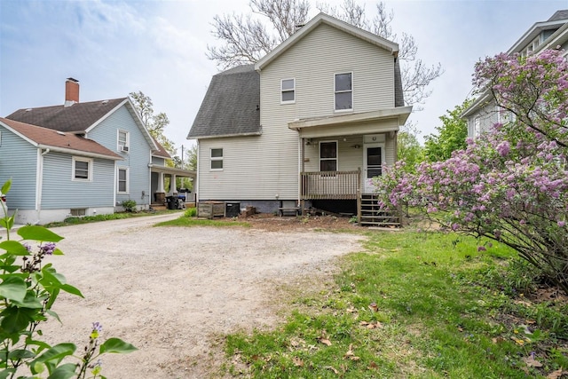 back of property featuring a shingled roof and driveway