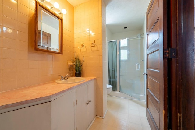 bathroom featuring tile walls, a stall shower, vanity, tile patterned floors, and toilet