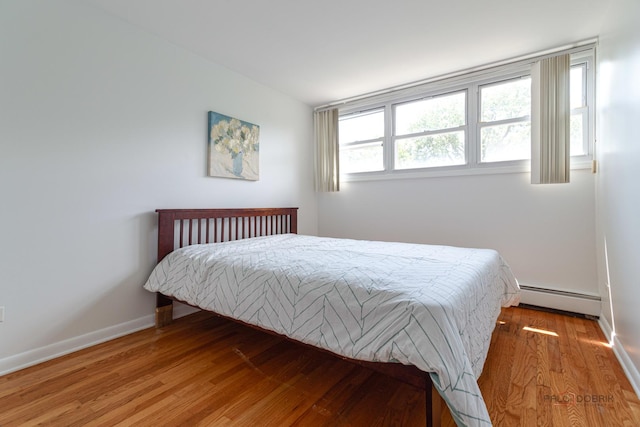 bedroom with baseboards, baseboard heating, and wood finished floors