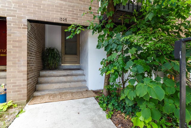 doorway to property featuring brick siding
