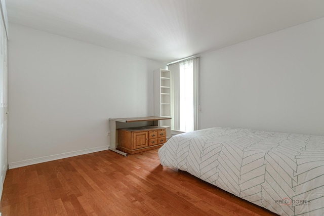bedroom with baseboards, multiple windows, and light wood-style flooring
