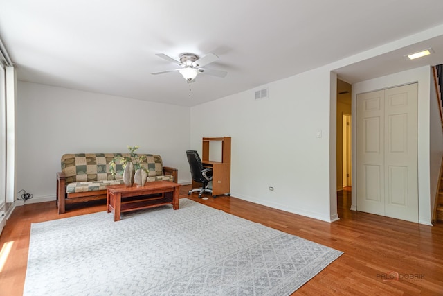 living area with a ceiling fan, visible vents, baseboards, and wood finished floors