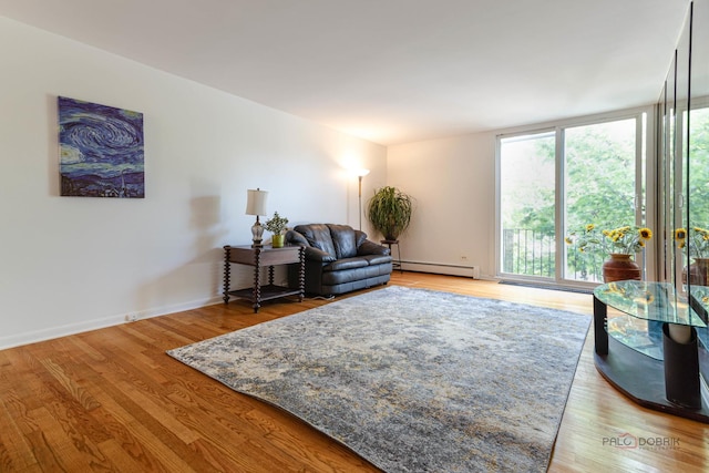living area featuring baseboards, wood finished floors, and a baseboard radiator
