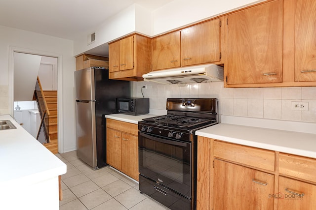 kitchen featuring light countertops, under cabinet range hood, backsplash, light tile patterned flooring, and black appliances