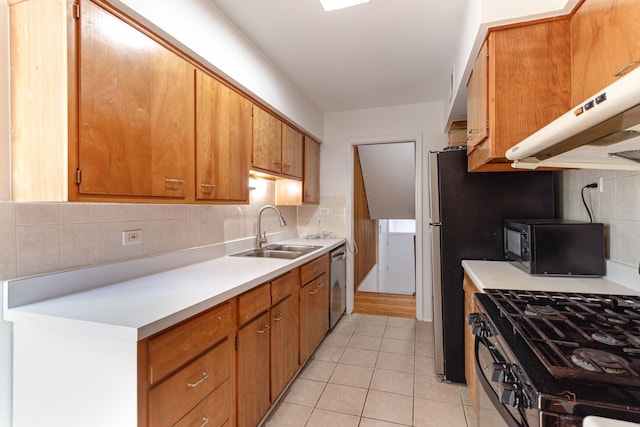 kitchen with black appliances, light countertops, a sink, and light tile patterned floors