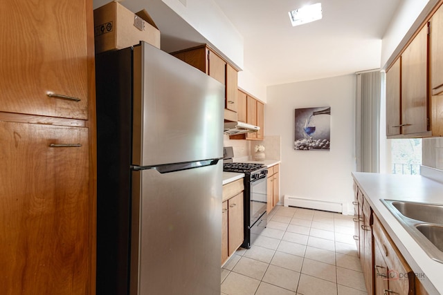 kitchen with decorative backsplash, light tile patterned flooring, a baseboard heating unit, black gas range, and freestanding refrigerator
