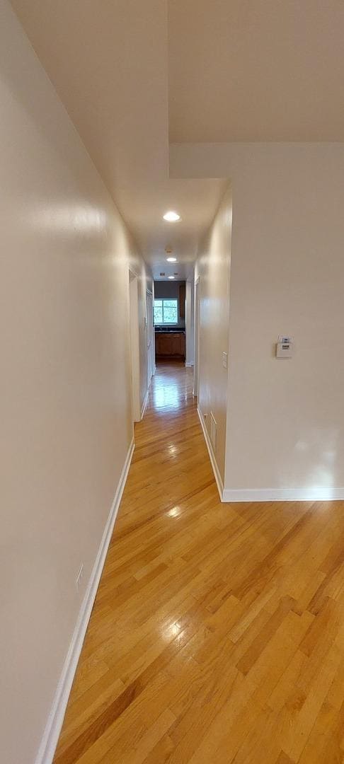 hallway with baseboards and light wood-style floors