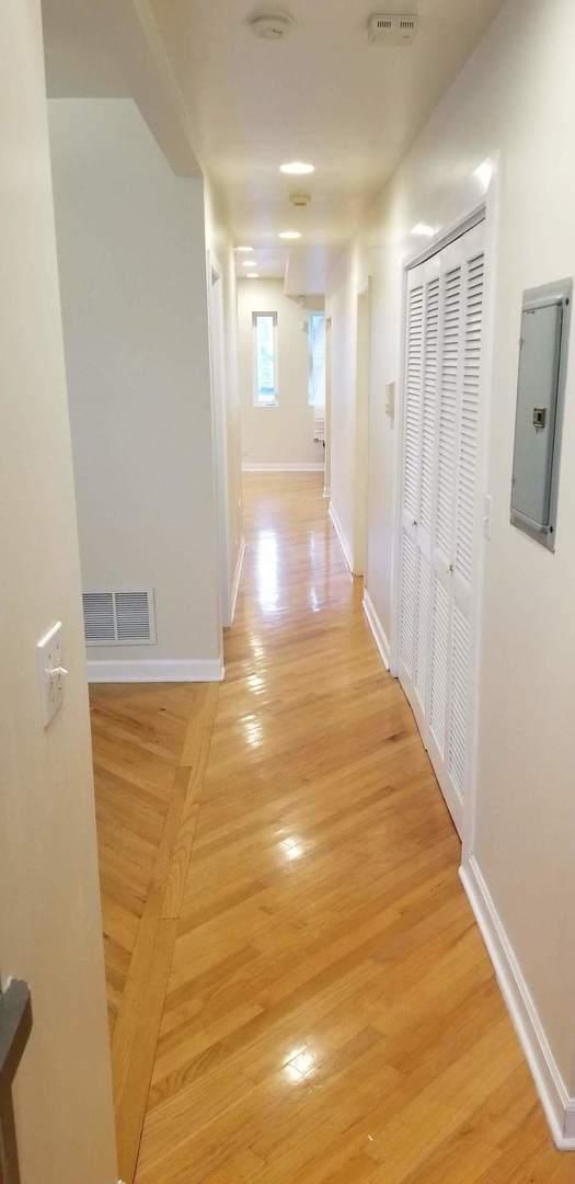 hallway featuring electric panel, baseboards, visible vents, and light wood finished floors