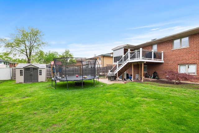 back of property featuring fence, a trampoline, a storage shed, stairway, and an outbuilding