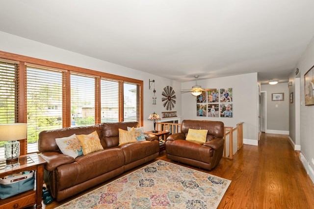 living room featuring baseboards, ceiling fan, and wood finished floors