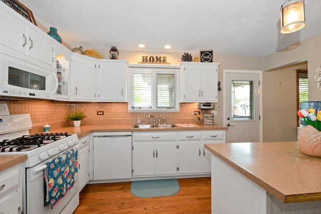 kitchen with decorative backsplash, white appliances, light countertops, a sink, and light wood-style flooring