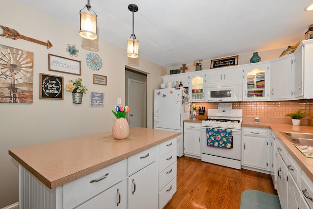 kitchen featuring backsplash, wood finished floors, light countertops, white appliances, and white cabinetry