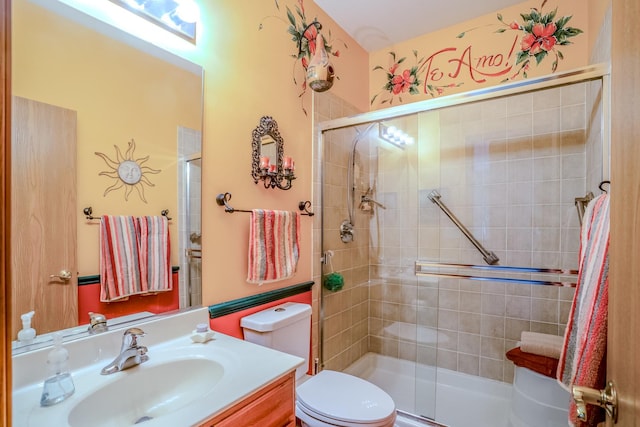 bathroom with a tile shower, toilet, and vanity