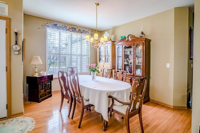 dining area featuring baseboards, light wood-style flooring, and a chandelier
