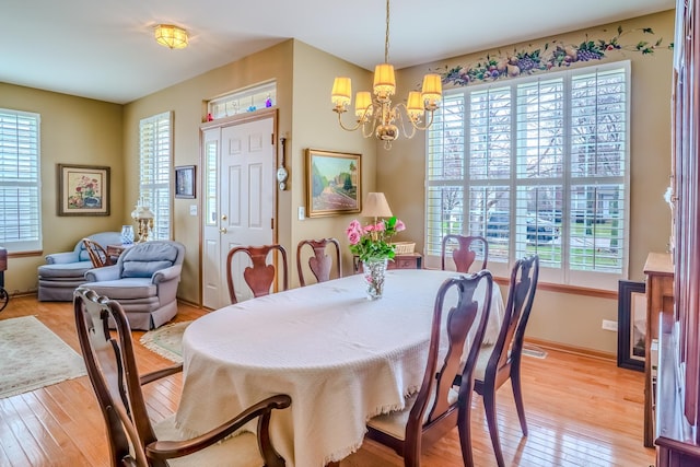 dining room featuring baseboards, a chandelier, and light wood-type flooring