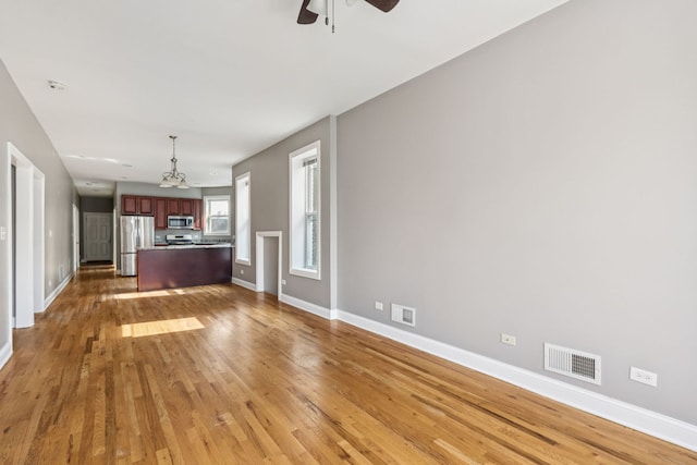 3220 W Polk St, Chicago, IL 60624 - unfurnished living room with light wood-style floors, ceiling fan, baseboards, and a chandelier