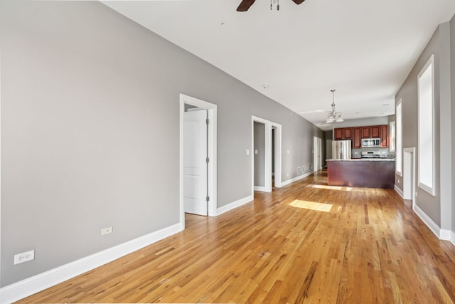 3220 W Polk St, Chicago, IL 60624 - unfurnished living room featuring a ceiling fan, light wood-style flooring, baseboards, and a chandelier