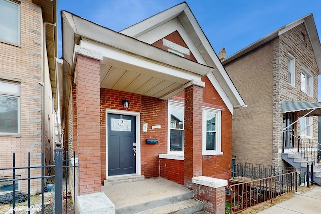 property entrance featuring brick siding and fence
