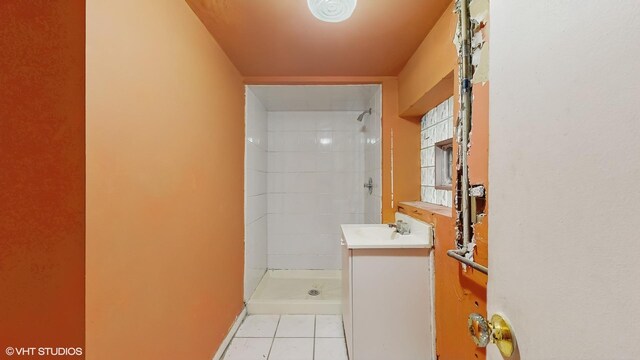 bathroom with a tile shower, tile patterned flooring, and vanity